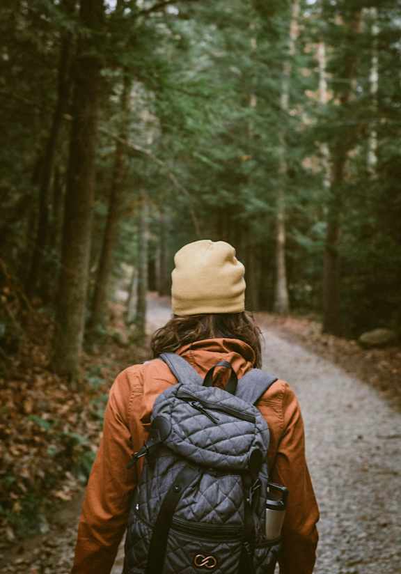 A person with a backpack is walking on a forest path.
