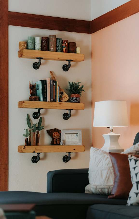 A living room with a couch, a lamp, and two wooden shelves with decorative items.