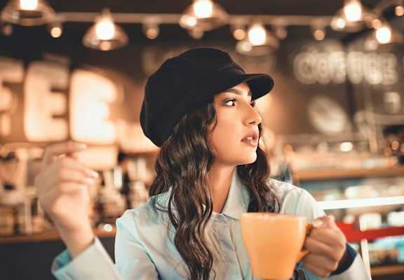 a woman sitting at a table with a cup of coffee