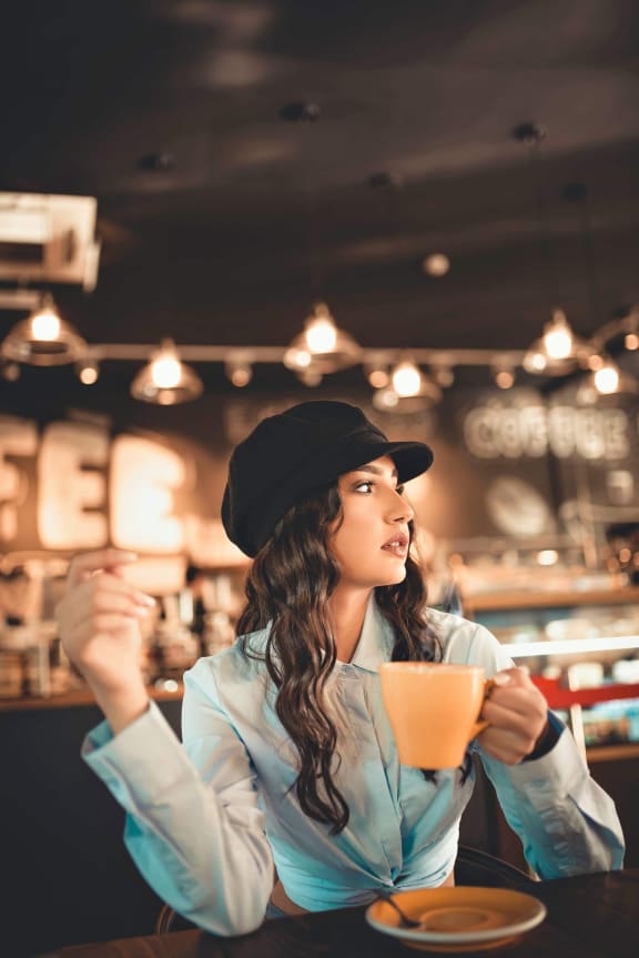 a woman sitting at a table with a cup of coffee