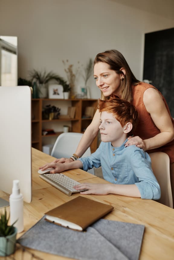 a mother and son looking at a computer screen