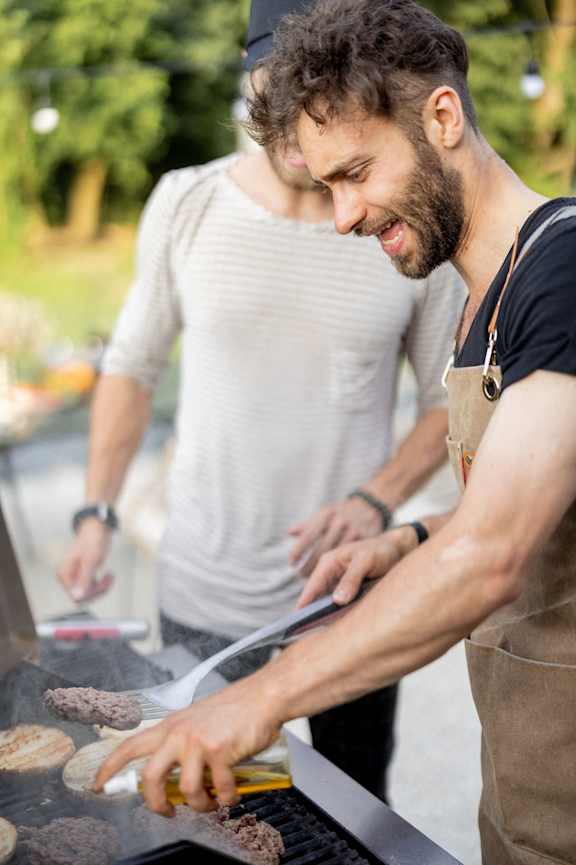 A man grilling hamburgers at a barbecue.
