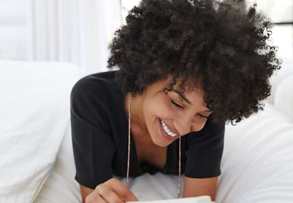 a woman reading while relaxing on a bed