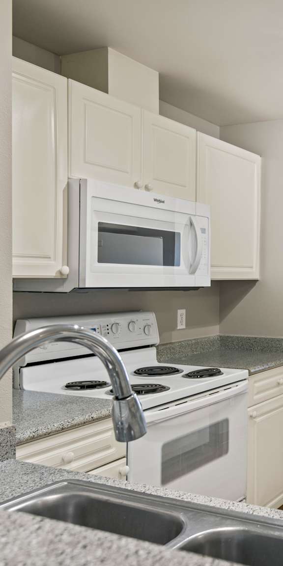 A kitchen with a white stove top oven and a white microwave above it.