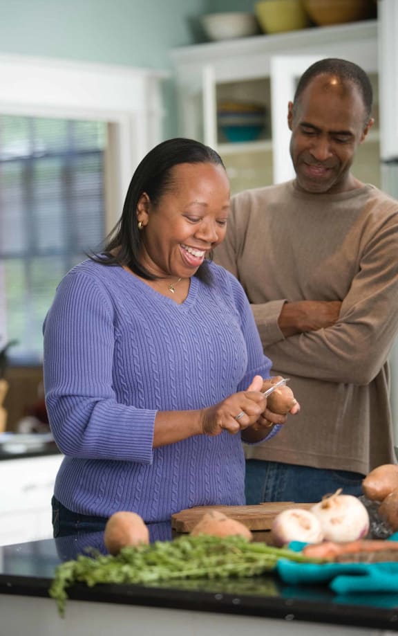 a man and woman standing in a kitchen preparing food