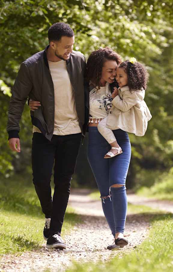 a man and woman walking down a path with a young girl in their arms