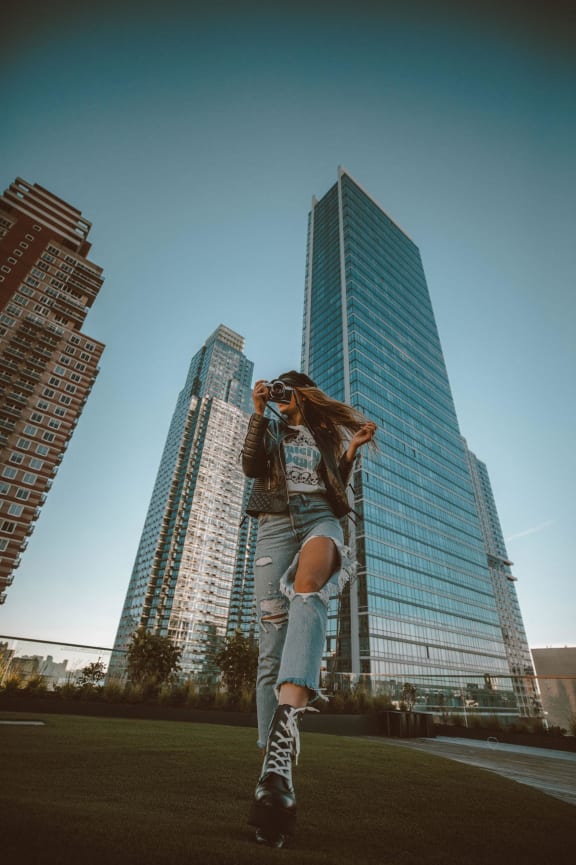 a woman jumping in the air in front of tall buildings