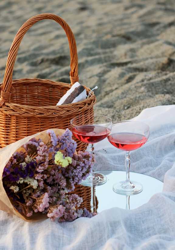 Picnic Setup with Basket, Wine Glasses, and Flowers