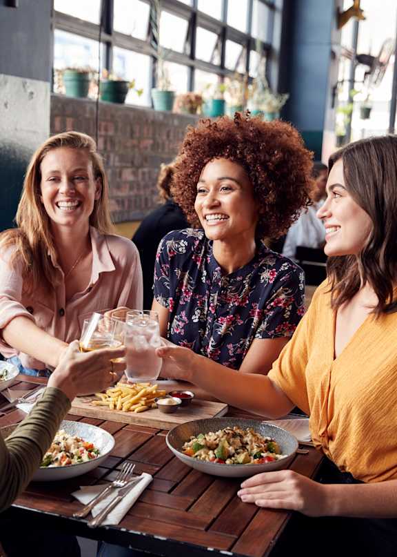 Friends Smiling while Having Food and Drinks Together