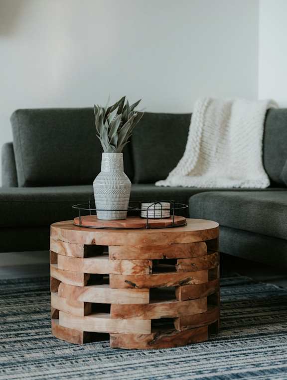 A wooden crate table with a vase and a plant on it.