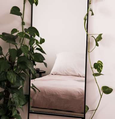 a bedroom with a large mirror and a bed with a white pillow