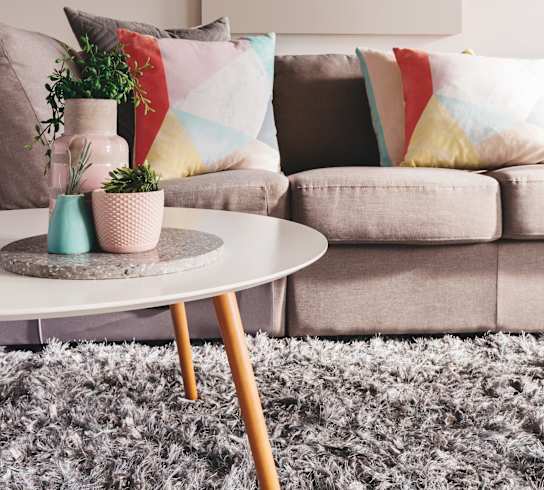 Living room with a sofa and coffee table with potted plants at Rolling Hills Apartments, Oregon