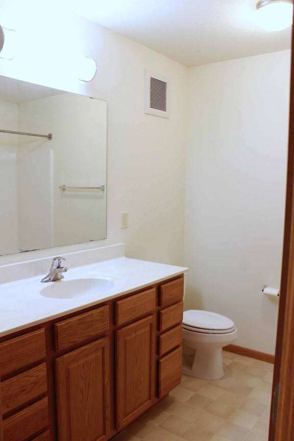 A bathroom with a toilet, sink and mirror.