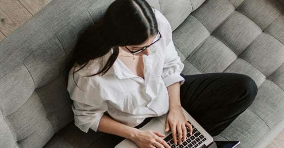 a woman sitting on a couch with a laptop