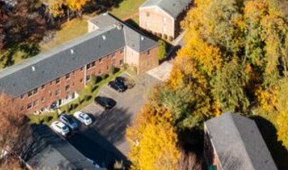 An aerial view of a building surrounded by trees with autumn foliage.