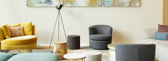 A living room with a yellow chair and a grey ottoman.