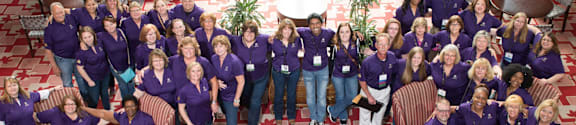 A group of people wearing purple shirts are posing for a photo.