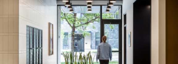 A woman is walking through a glass door into a courtyard.