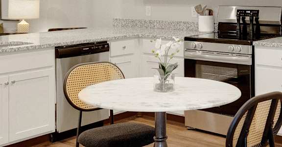 A kitchen with a table and chairs.