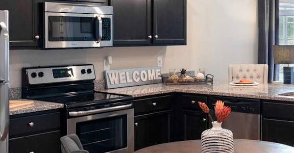 a kitchen with black cabinets and stainless steel appliances and a table