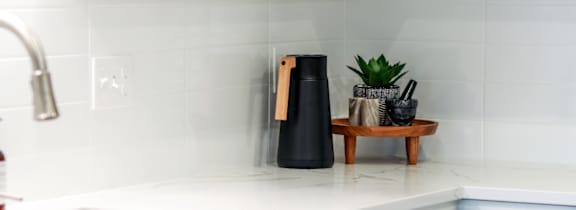 a cutting board with a plant and a vase on a kitchen counter