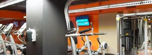 A gym with orange walls and a variety of exercise equipment.