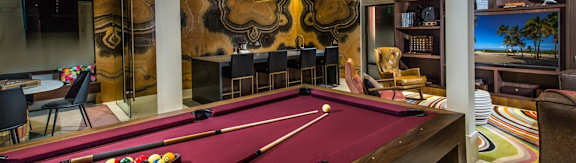 A pool table with a red cloth and a white cue ball.