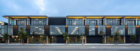 A modern building with a glass facade and a large mural on the side.