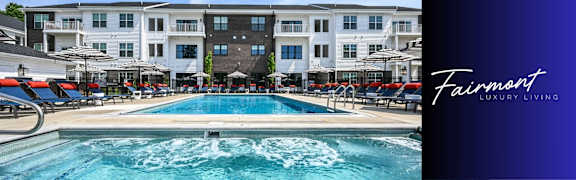 A large building with a pool in front and a sign that says Fairmont Luxury Living.