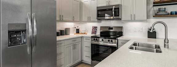 a walk in closet with white cabinets and a mirror