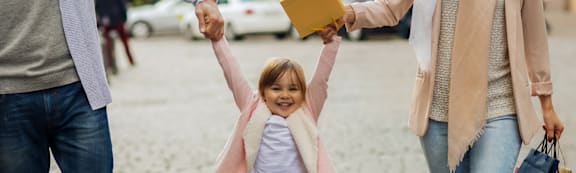 A little girl is being held up by two adults.