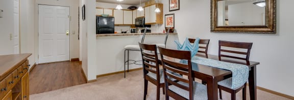 a dining area with a table and chairs and a kitchen in the background
