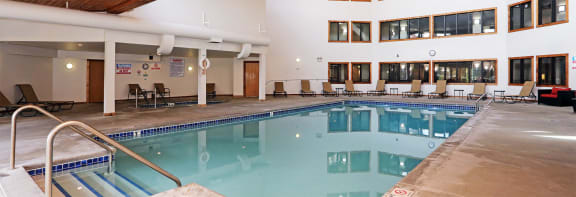 a large indoor pool with lounge chairs and a ceiling fan