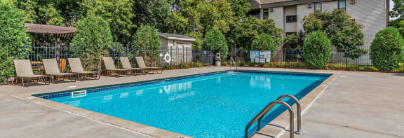 a swimming pool with a fence around it and trees in the background
