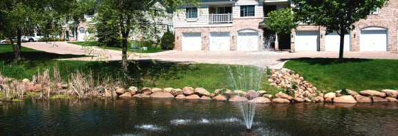 a fountain in a pond in front of a house
