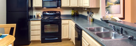 a kitchen with white cabinets and black appliances