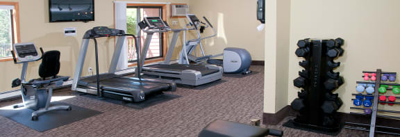a gym with exercise equipment and a wall mounted tv