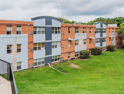 A building with a black gate and a green lawn in front.