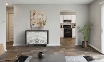 Model Living Room with Wood-Style Flooring and View of Kitchen at Parc at Creekside Apartments in Kansas City, MO-HERO.