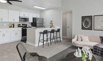 Model Living Room with Carpet and View of Kitchen with Wood-Style Flooring at Crystal Creek Apartments in Phoenix, AZ-HERO.