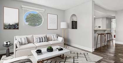 Model Living Room with Wood-Style Flooring and View of Kitchen at Stillwater Apartments located in Glendale, AZ-HERO.