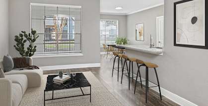 Model Living Room with Wood-Style Flooring and View of Kitchen at Park West Apartments located in Houston, TX-HERO.