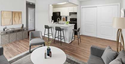 Model Living Room and Kitchen with Wood-Style Flooring at Vue at Baymeadows Apartments located in Jacksonville, FL-HERO.