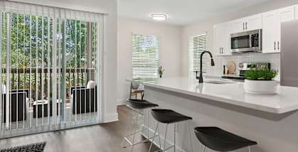 Model Kitchen with White Cabinets, Wood-Style Flooring and Patio Accessibility at Park at Caterina Apartments located in Charlotte, NC-HERO.