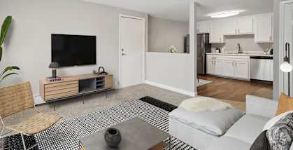 Model Living Room with Carpet and View of Kitchen at Middlesex Crossing Apartments located in Billerica, MA-HERO.
