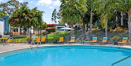 community swimming pool with yellow chairs around it and a building in the background