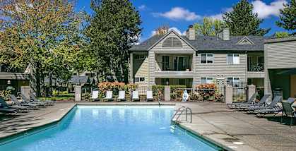 Community swimming pool with chairs and a house in the background