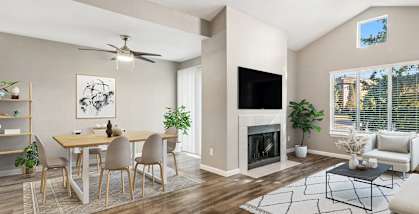 Model apartment living room with a fireplace and a dining room table