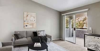 Model apartment living room with a couch and a chair and a sliding glass door
