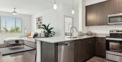 Model Kitchen with Dark Wood Cabinets, Wood-Style Flooring and View of Living Room at Parc Roundtree Ranch Apartments located in Peoria, AZ-HERO.